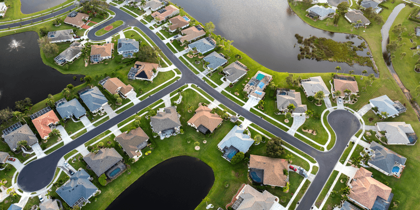 Aerial view of a suburban neighborhood with houses, roads, and ponds.
